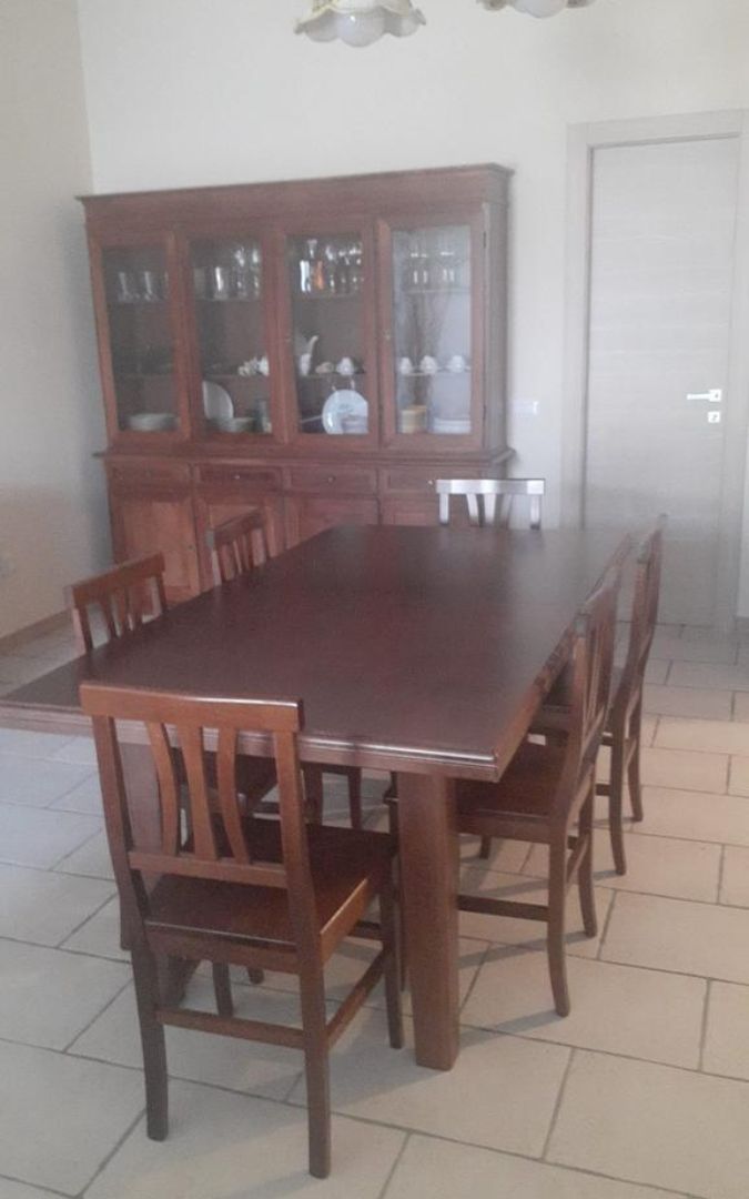 Arredamento arte povera: tavolo fratino allungabile in legno noce con credenza sullo sfondo.